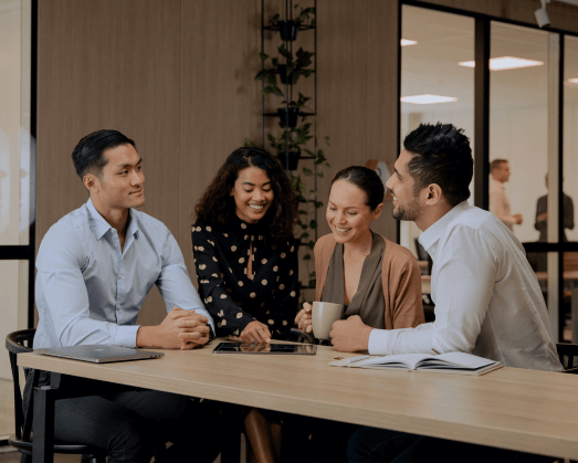 Cuatro compañeros de trabajo que colaboran en una mesa.