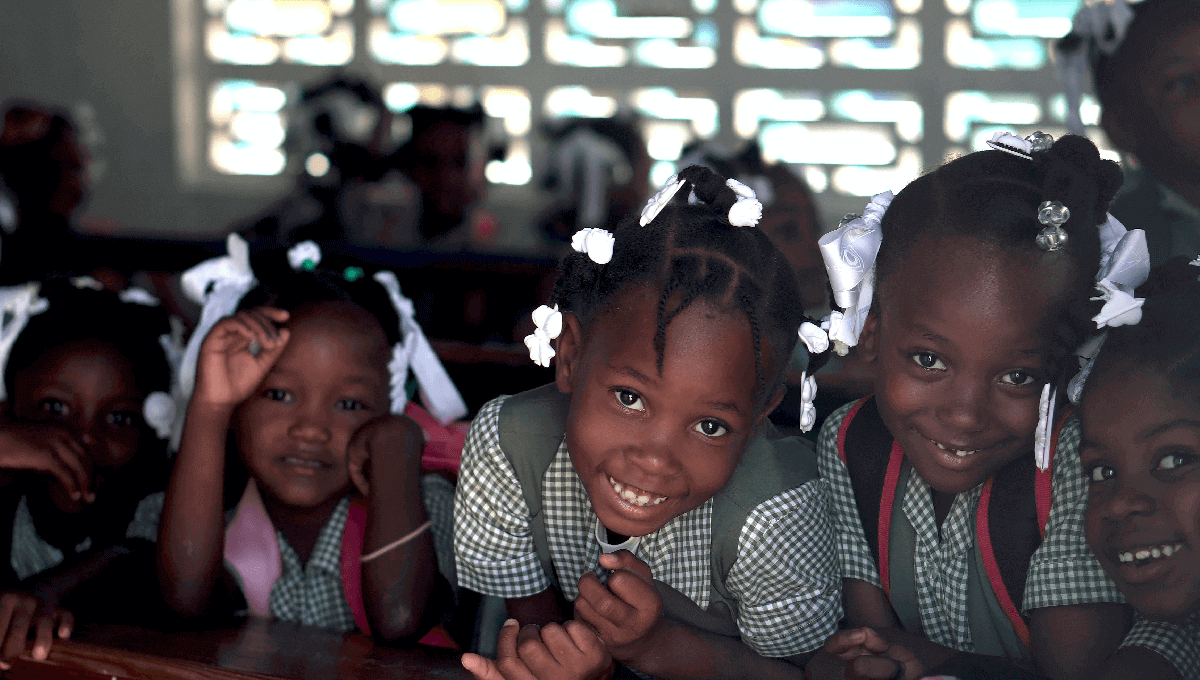 Five girls from the Education Outcomes Fund program are smiling at the camera