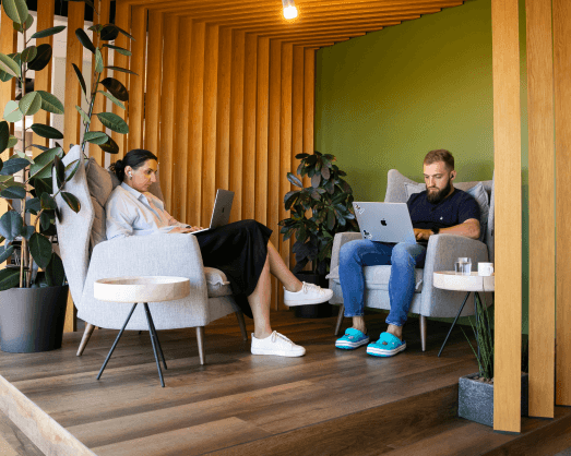 Two coworkers sitting next to another working on their laptops